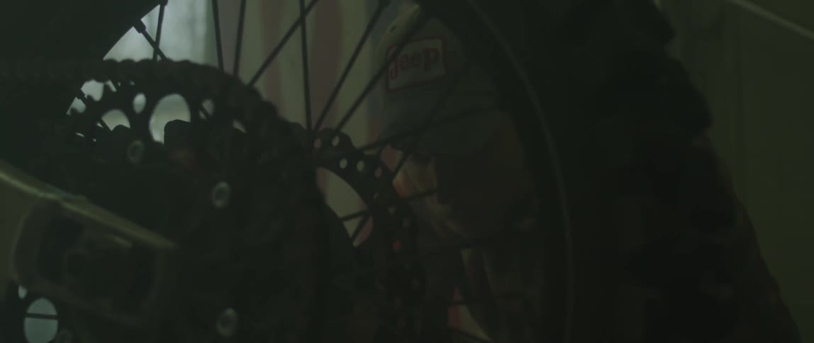Man with cap in front of american flag repairs bike at the garage