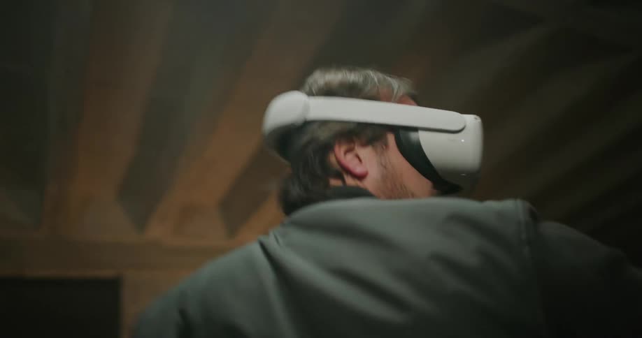A man swings his arms around and spins in a circle as he plays a virtual reality game
