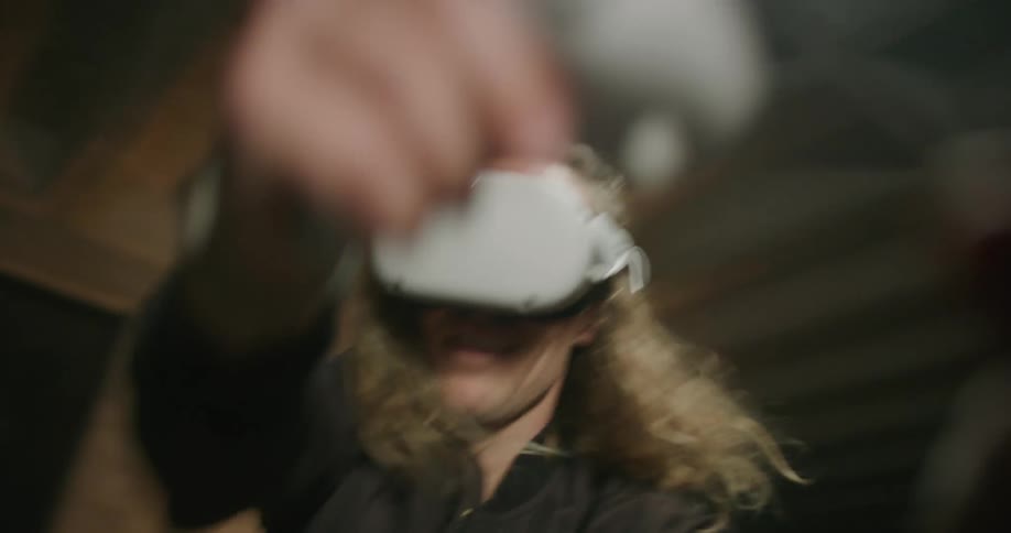Young blonde long haired man plays video game with 3d virtual reality goggles over his eyes