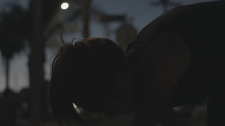 A woman stretches outdoors at night