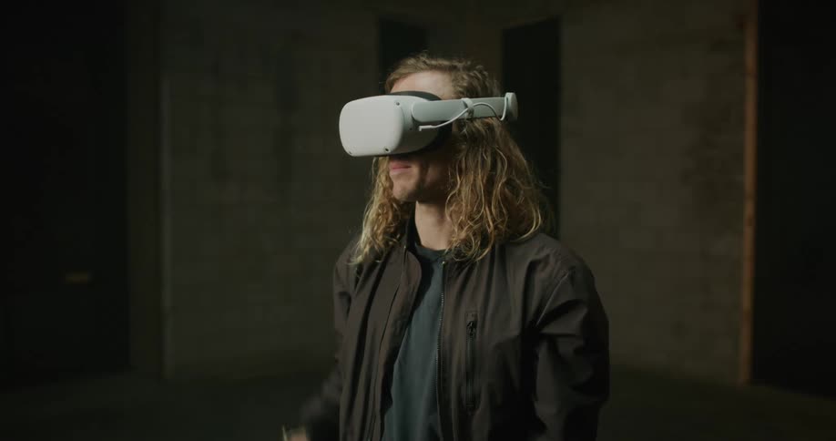 Young blonde long haired man puts on 3d virtual reality goggles over his eyes