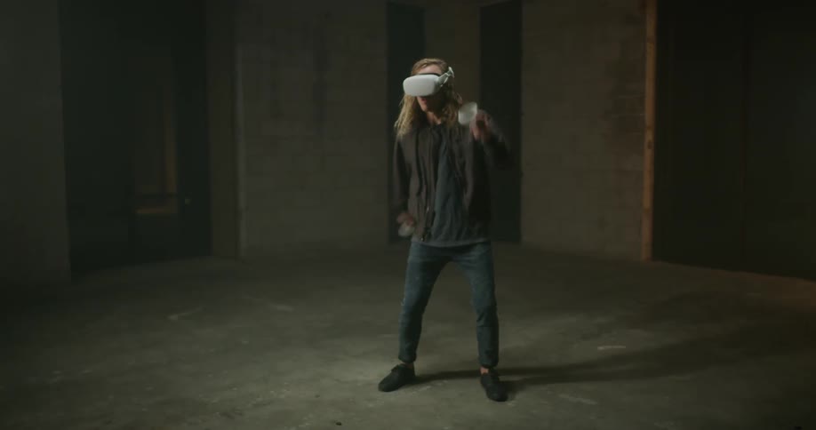 Man swing his arms playing a virtual reality game in a vacant room