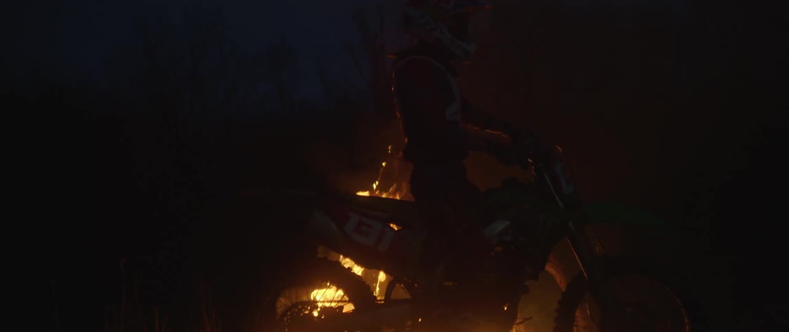 A motorcycle stops in front of a bonfire burning in the darkness of night