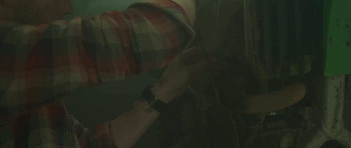 A man uses a screwdriver to tighten something as he fixes it