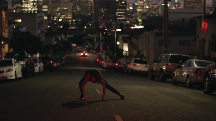 A woman is stretching in the middle of a street at night