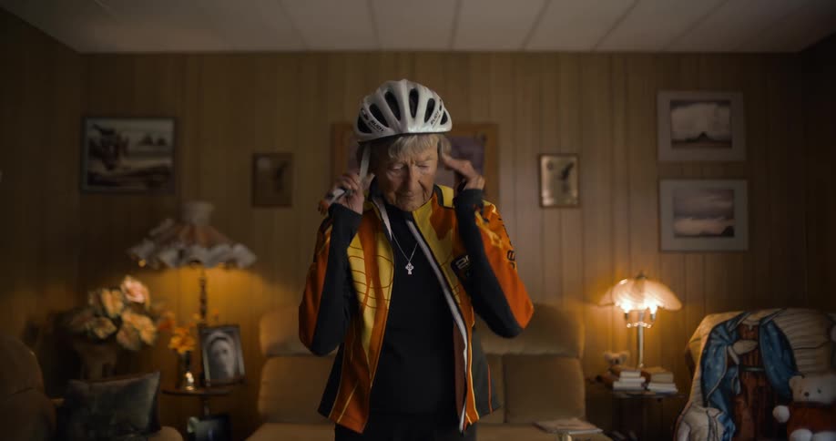 Elderly woman makes the sign of the cross before putting a bicycle helmet on