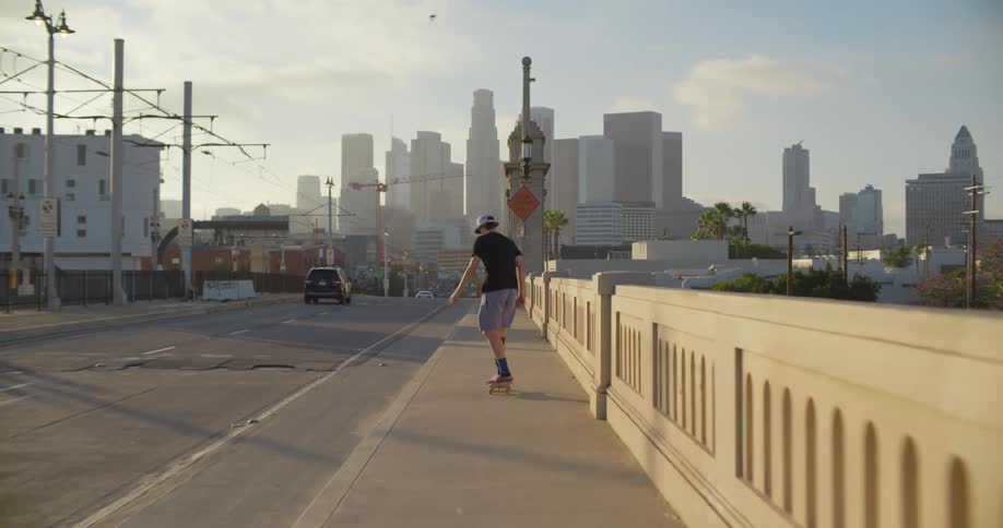 A boy does tricks on a sidewalk as he rides a skateboard downtown