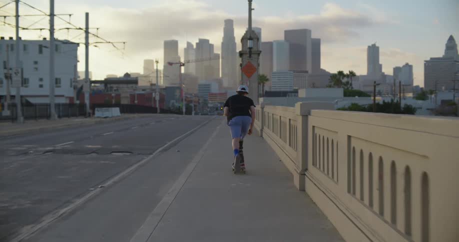 A teenager falls off his skateboard after attempting a trick on a sidewalk downtown