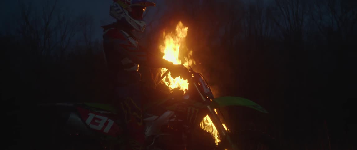 A motorcycle stops in front of a bonfire burning in the darkness of night