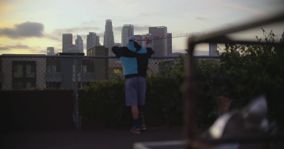 Young man looking at the city view over a fence