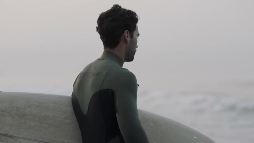 A man carries a surfboard into the ocean
