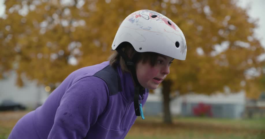 Young tired girl wearing a white helmet recovering her breath on the neighborhood street