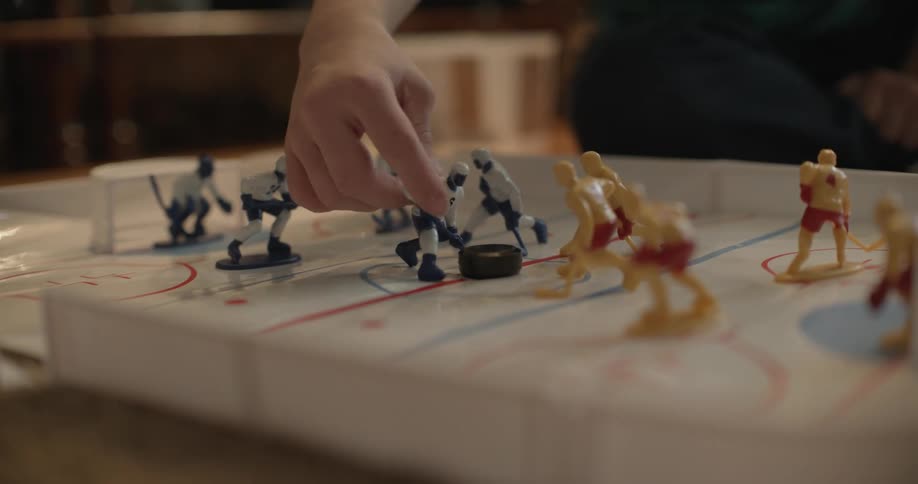 A child plays with hockey player figurines on a toy ice rink