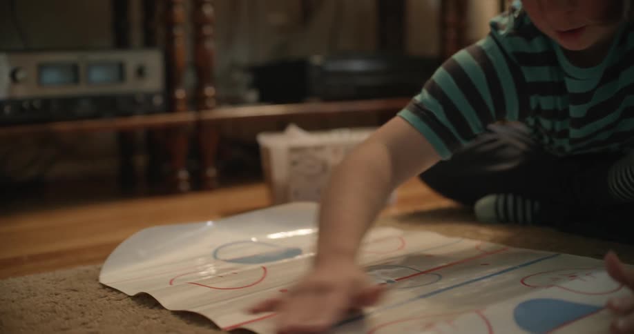 A girl with Downs Syndrome is sitting on the floor near a television and sets up a game board
