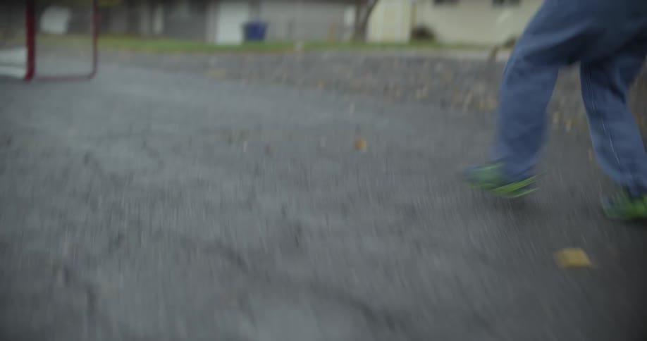 A person plays hockey in a neighborhood street by themself and cheers after making a goal
