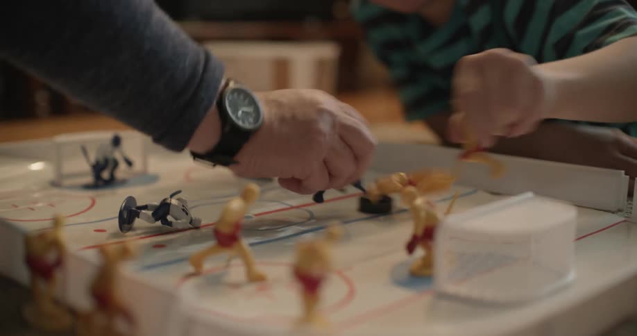 A man and a girl are playing a game of table hockey