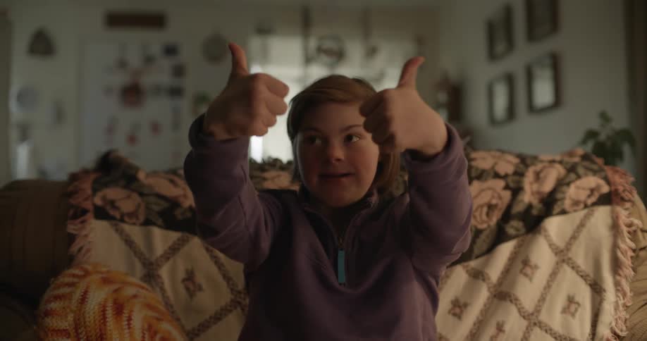 A woman sits down waving thumbs up around