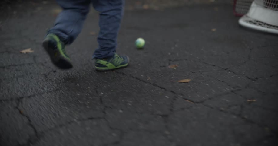 Young girl playing alone on the neighborhood streets with street hockey equipment