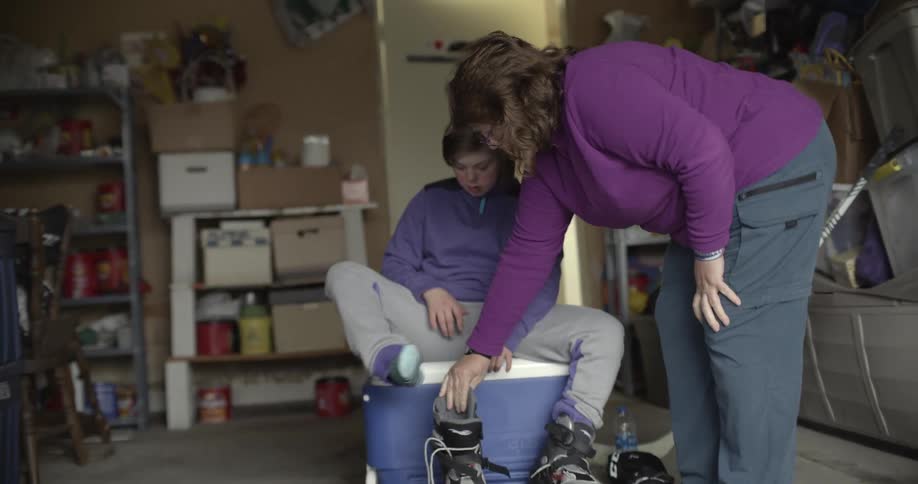 A woman opens up roller skates and hands them to another person to put on