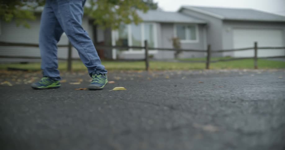 Person plays street hockey standing in street