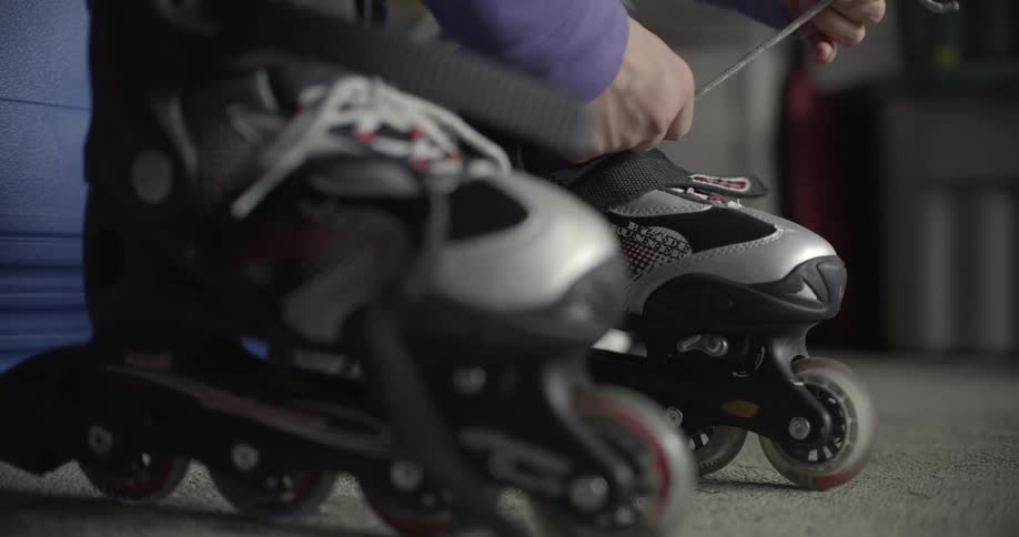 A child ties laces on their rollerblades