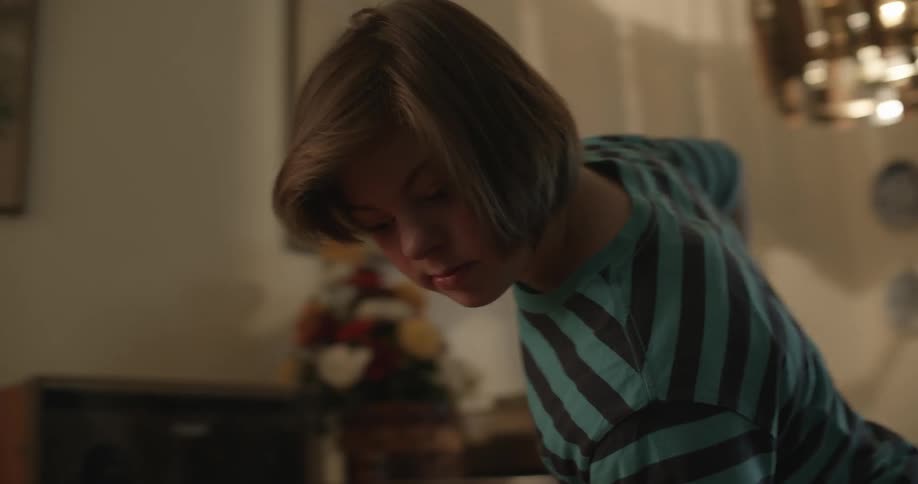 A child is leaning over pushing something inside a house