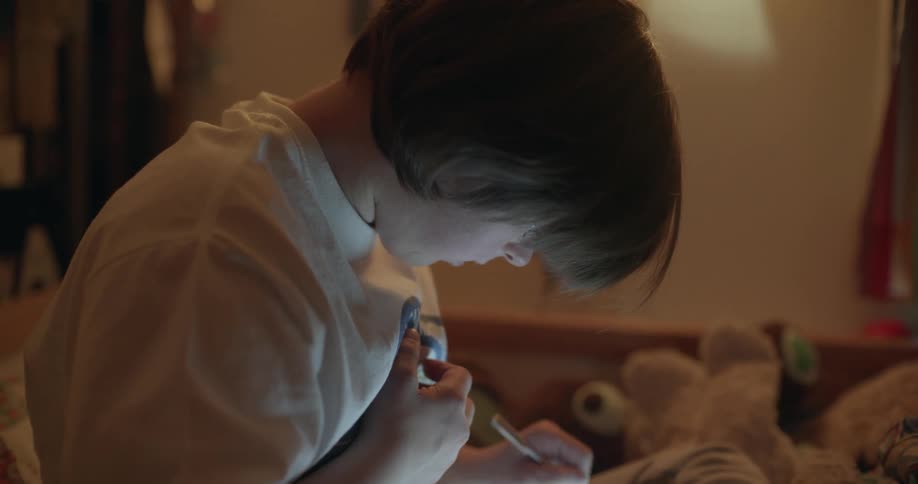 Teenage girl sketches on tablet while sitting on bed near stuffed toys