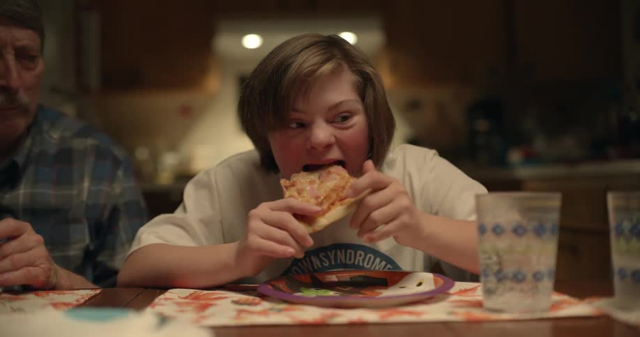 A person eats pizza sitting at a dinner table