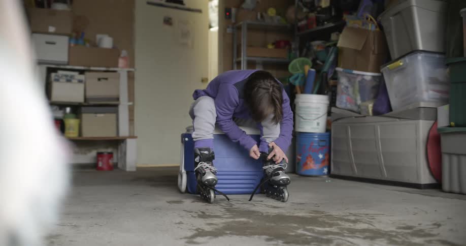 Person sits on ice chest in garage to put on their inline skates