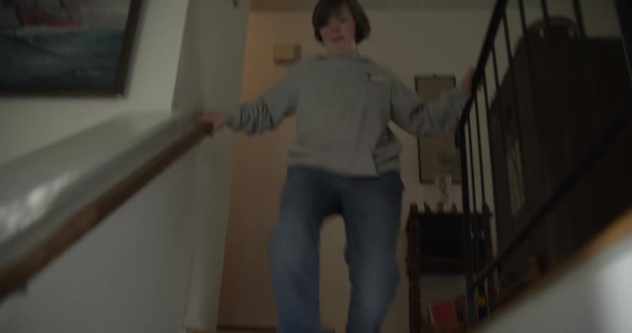 A girl runs excitedly down the stairs in a house