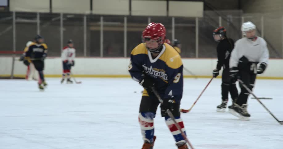 Hockey players train with hockey pucks in ice rink