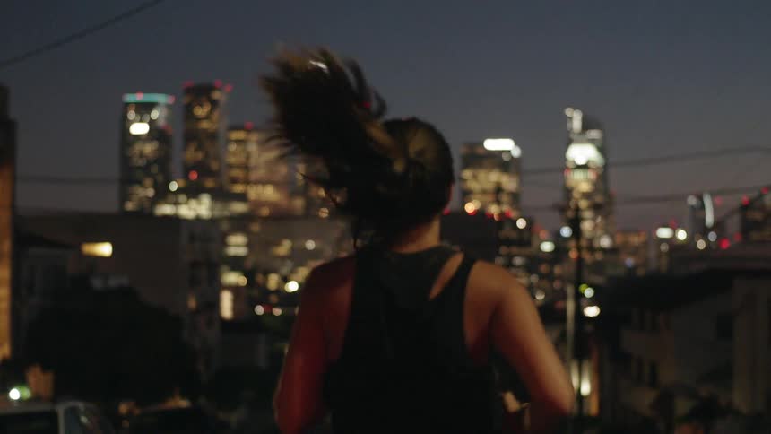 A woman jogs down the street at sunset