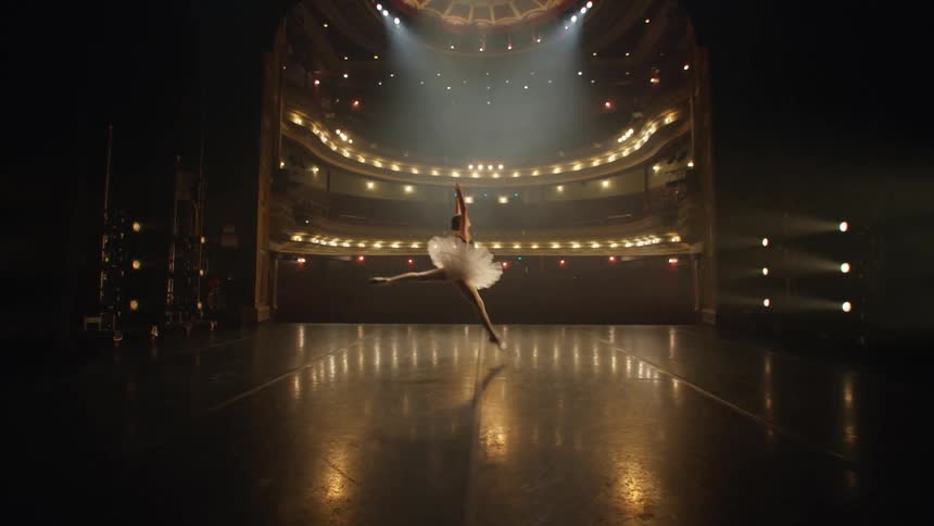 A ballerina jumps on stage dancing