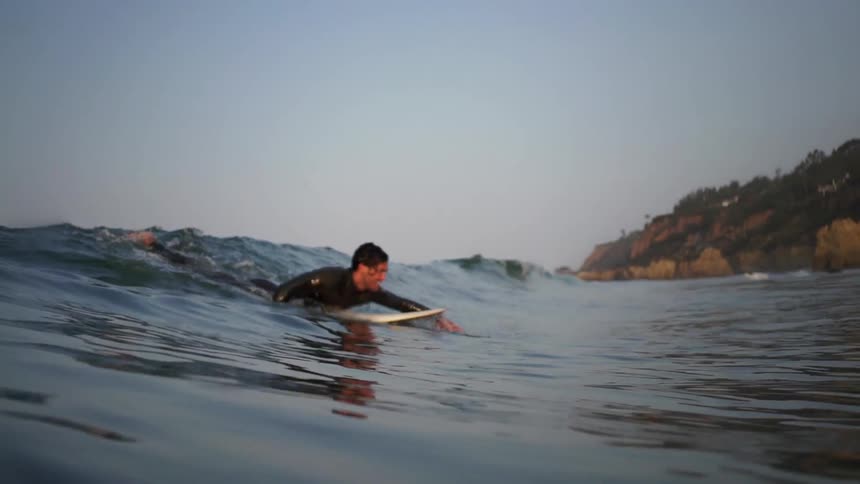 A man paddles to ride a wave in