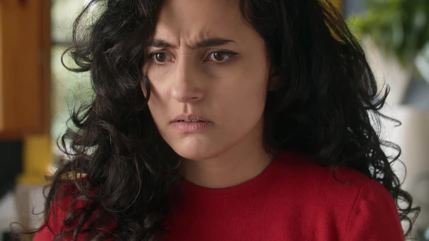 A woman looks upset as she rubs her stomach