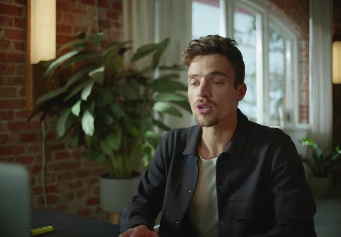 A man sits at home in front of his computer and talks as he video chats