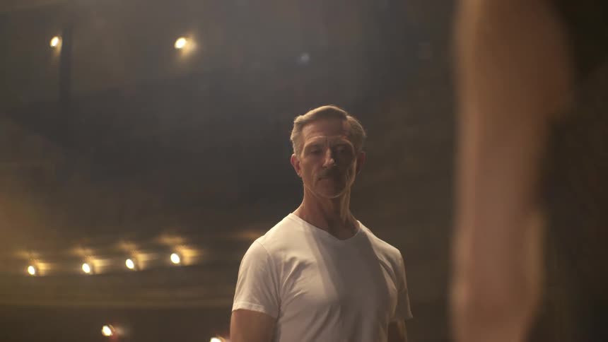 Male and female dancers face each other in empty theater