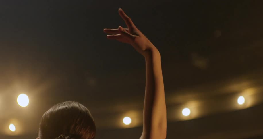 A woman is performing ballet hand arm raised in air