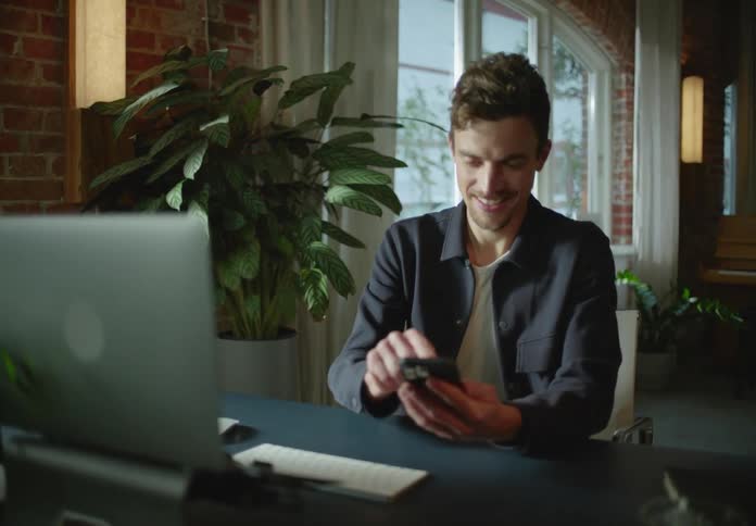 A man stops working to reply to a text on his phone