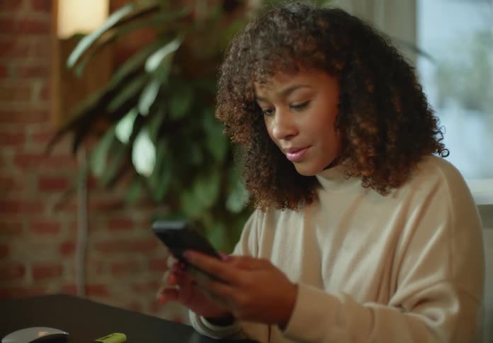 Young woman checking her smartphone while working from home