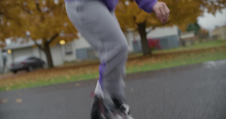 Woman watches her daughter learn to skate on inline skates on asphalt topped road in neighborhood