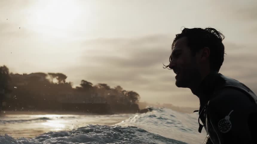 A man is riding a wave before turning at sunset