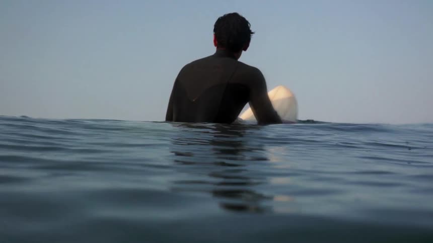 A man rides a surfboard in a body of water