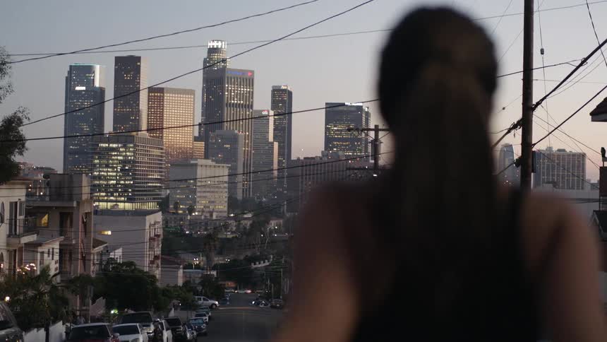 A woman in black stretches while looking toward the city