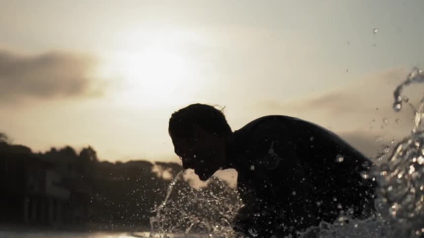 A man rides a wave at sunset