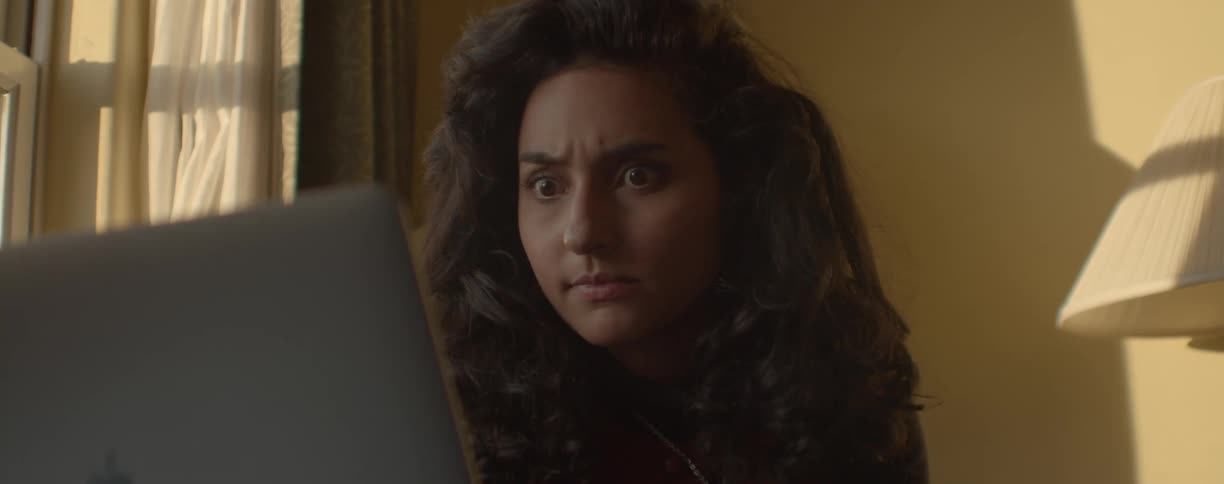 Womans expression changes to show different emotions as she watches computer screen