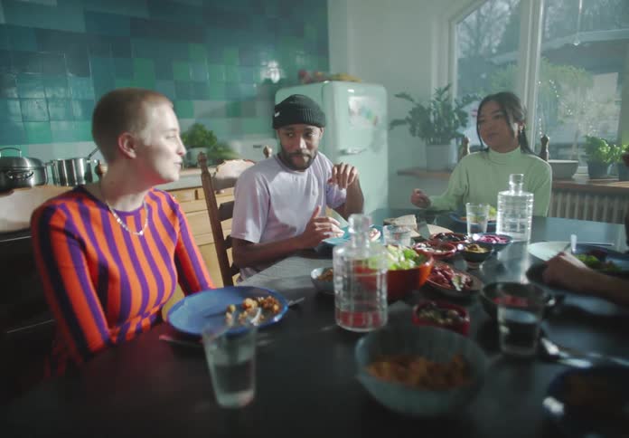 Friends sit around table eating in kitchen