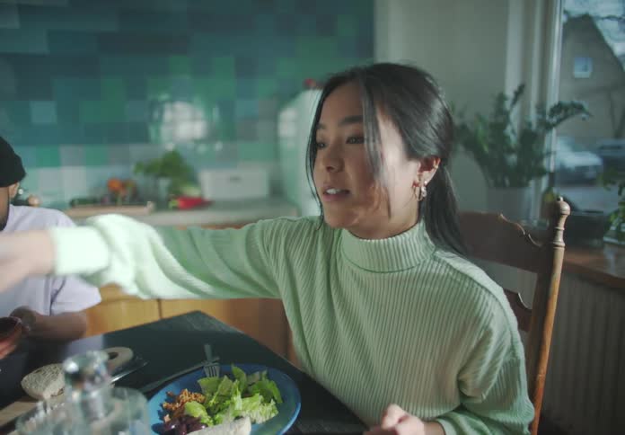 A woman passes a food bowl to another person at a dining table