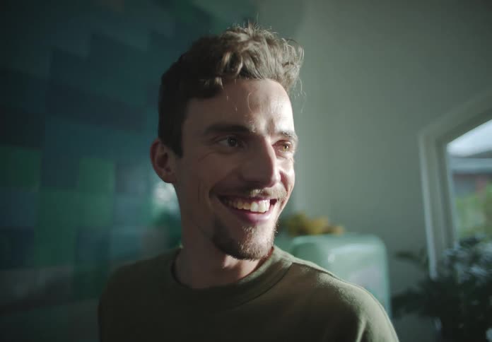 Man stands smiling and talking in kitchen before turning to counter
