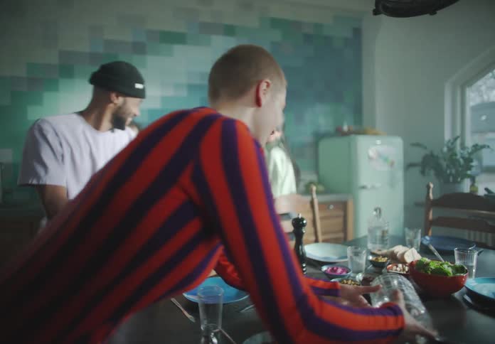 A group of young adults cook food in a large kitchen